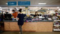 A cashier standing behind a protective barrier assists a customer at a Peter Harris Clothes store in Latham, N.Y. 